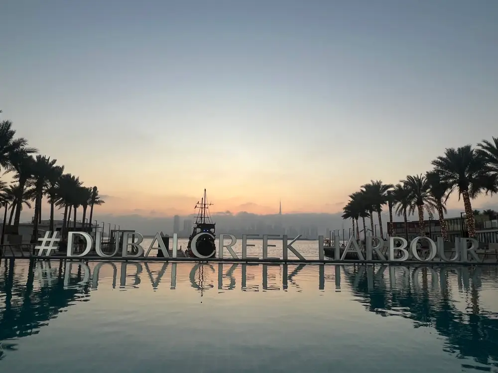 Palm-lined pool deck at dawn within the landscaped grounds of Dubai Creek Harbour
