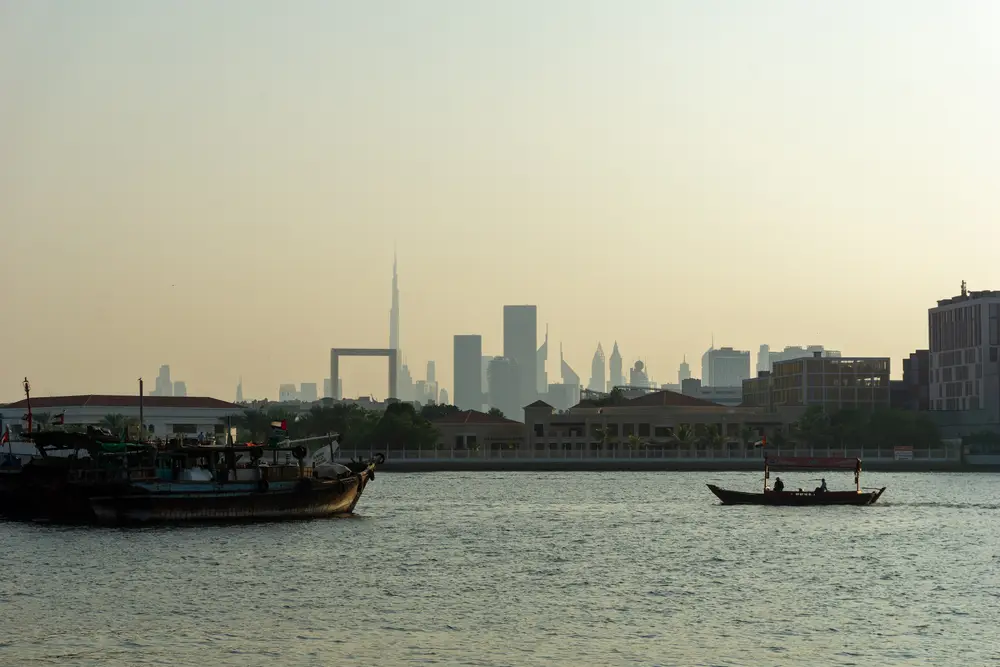 Dubai Creek with traditional boats and the city skyline beyond at dusk