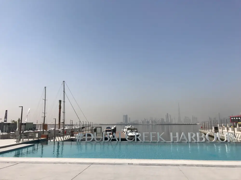 Waterfront pool deck with the Dubai Creek Harbour sign and skyline view across the creek